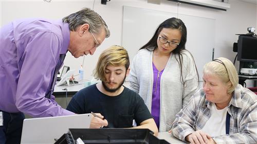 Oswego County e-NABLE team members and a student work together 